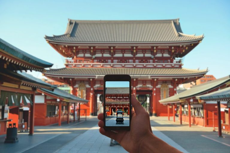 Shinto shrine with a mobile phone taking a photo of it.