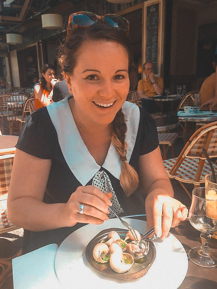 A lady sitting getting ready to eat escargot in Paris