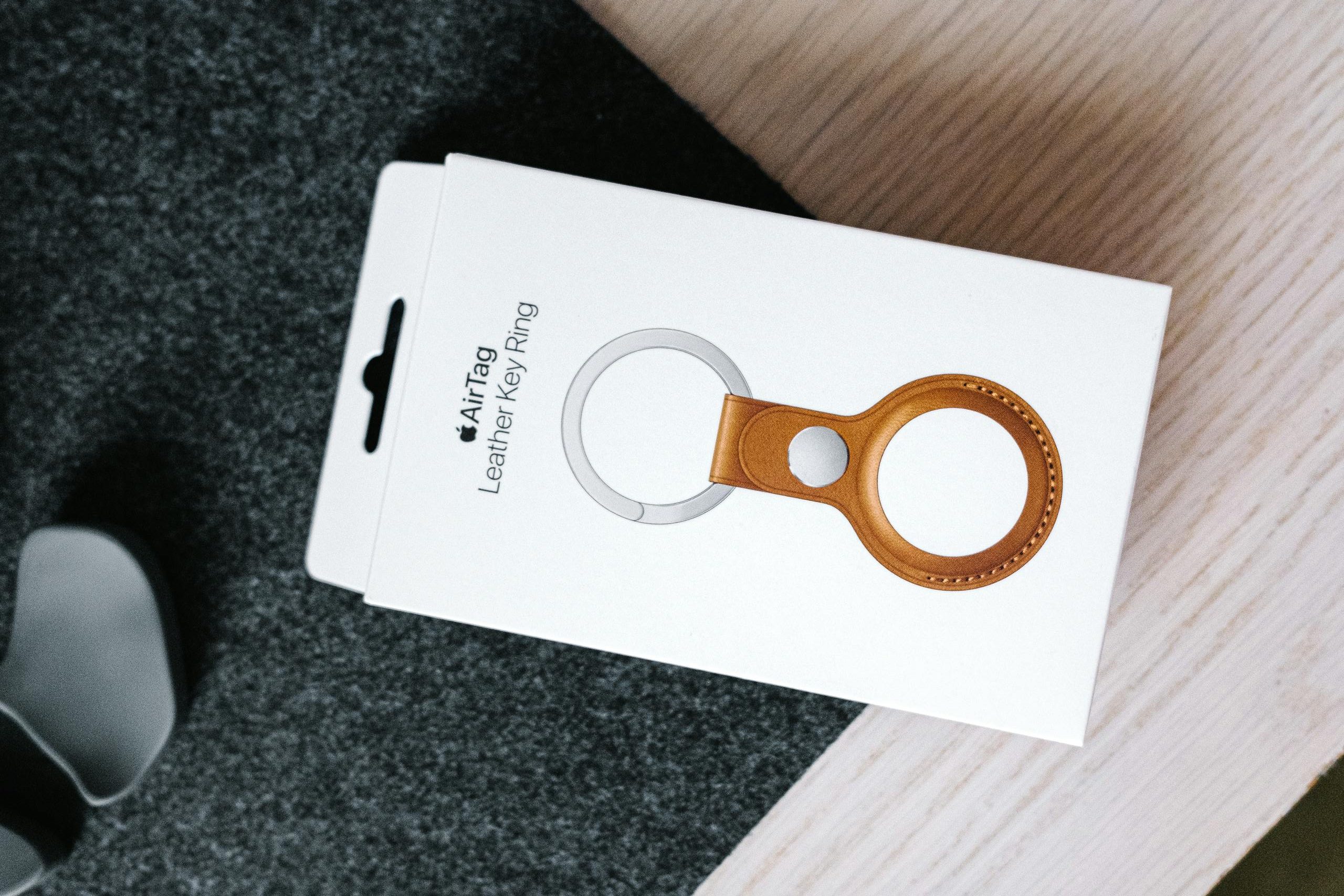 Vertical shot of an Apple AirTag leather key ring box placed on a wooden table surface.