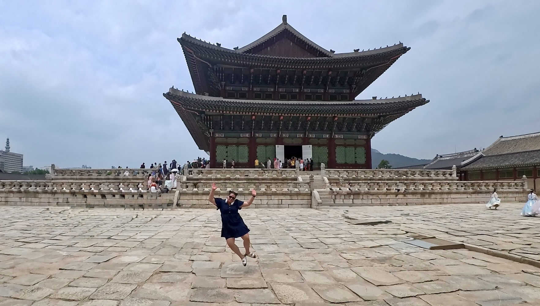 A girl in a blue dress jumping outside Palace in Seoul, Korea